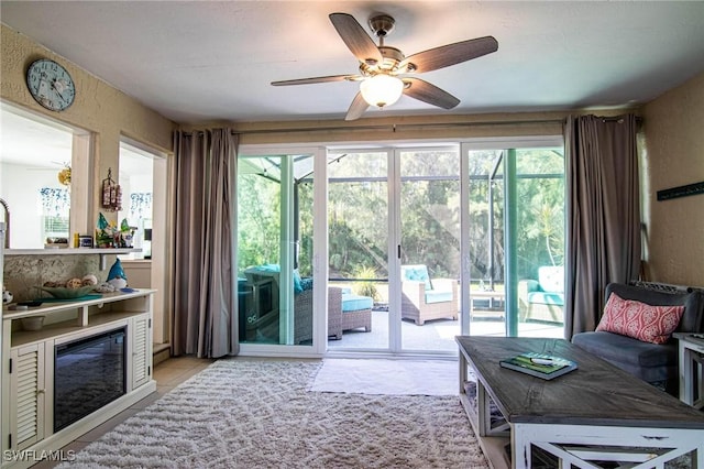 entryway with a ceiling fan and a glass covered fireplace