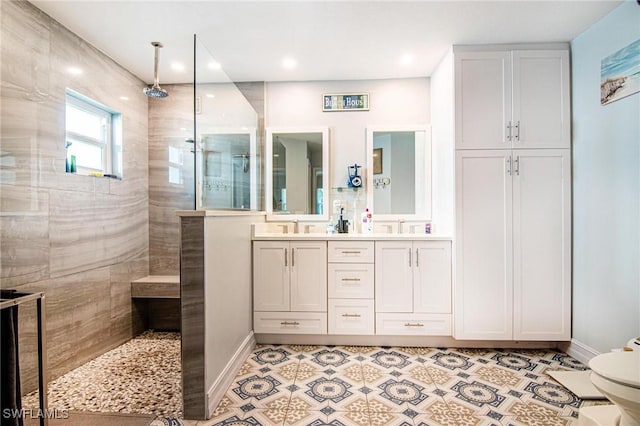 bathroom with double vanity, baseboards, a walk in shower, and a sink