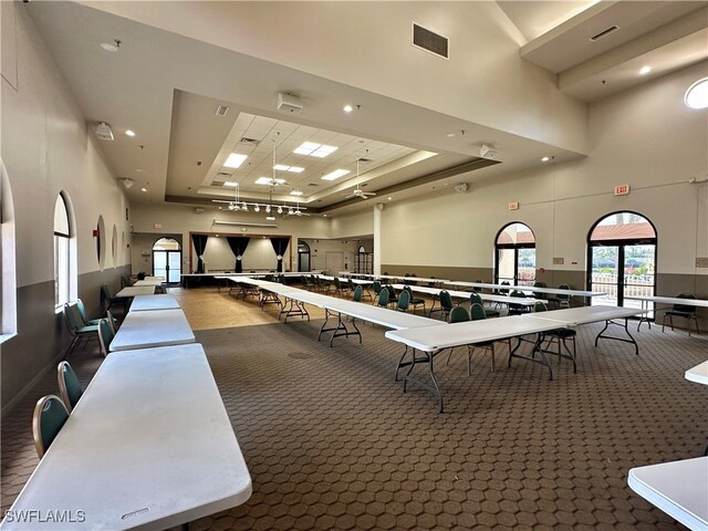 game room featuring a towering ceiling, a raised ceiling, and carpet floors