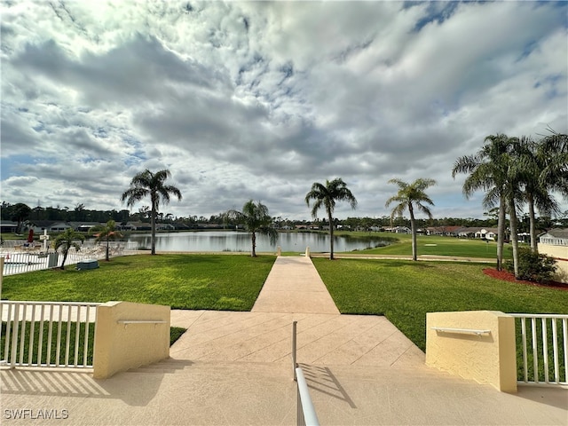 view of property's community with a water view and a lawn