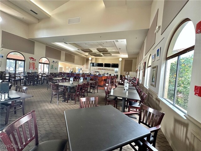 dining space with carpet floors and a towering ceiling