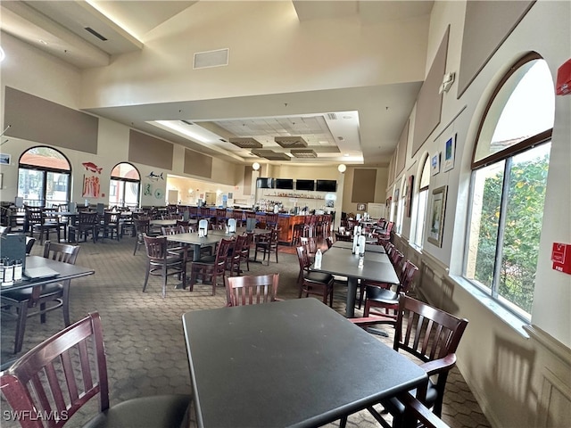 dining area featuring carpet flooring, visible vents, and a high ceiling