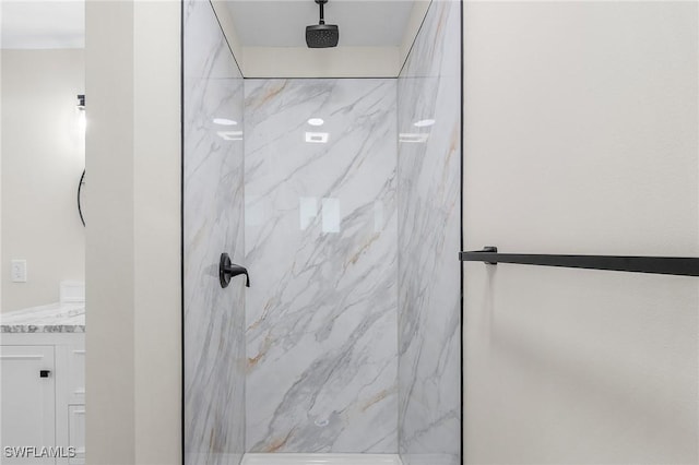 bathroom with a marble finish shower and vanity