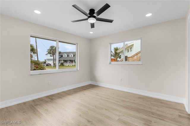 spare room featuring a healthy amount of sunlight, light wood-type flooring, baseboards, and recessed lighting