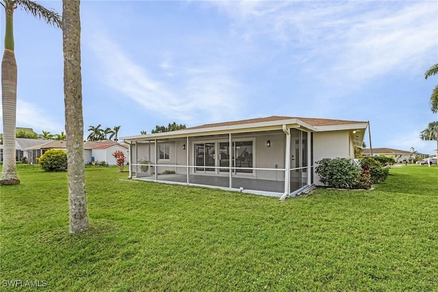 back of property featuring a sunroom, a yard, and stucco siding