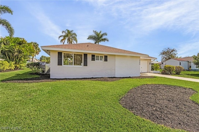 view of front of house with a front yard, driveway, an attached garage, and stucco siding