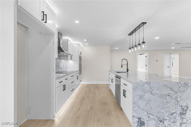 kitchen featuring light wood-style floors, a sink, wall chimney range hood, and dishwasher