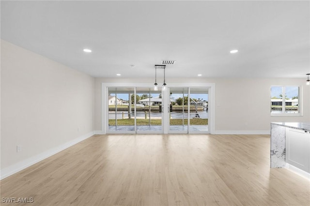 unfurnished living room featuring plenty of natural light and light hardwood / wood-style flooring