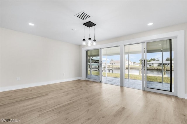 spare room with a water view and light wood-type flooring