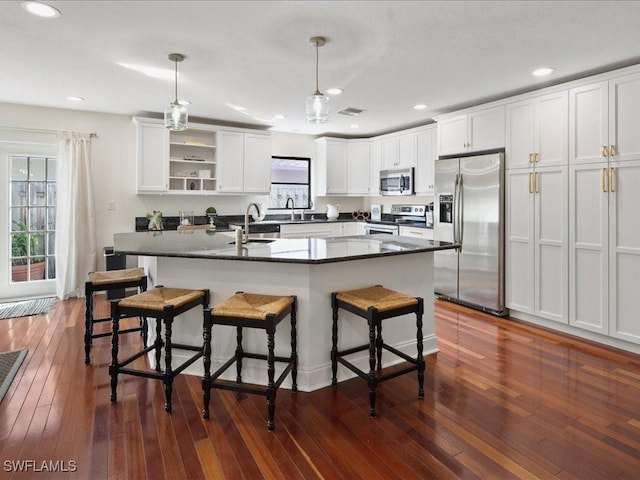 kitchen with stainless steel appliances, a kitchen bar, decorative light fixtures, and a kitchen island with sink