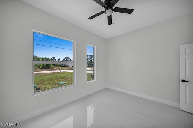 spare room with baseboards and a ceiling fan