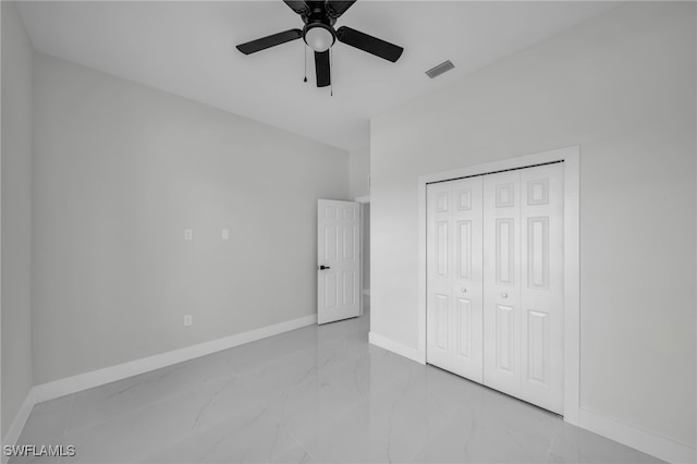 unfurnished bedroom featuring marble tiled flooring, baseboards, a closet, and a ceiling fan