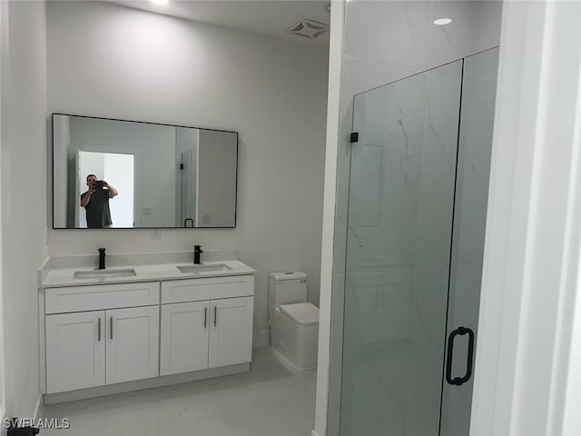 bathroom featuring marble look tiles, a marble finish shower, toilet, and double vanity