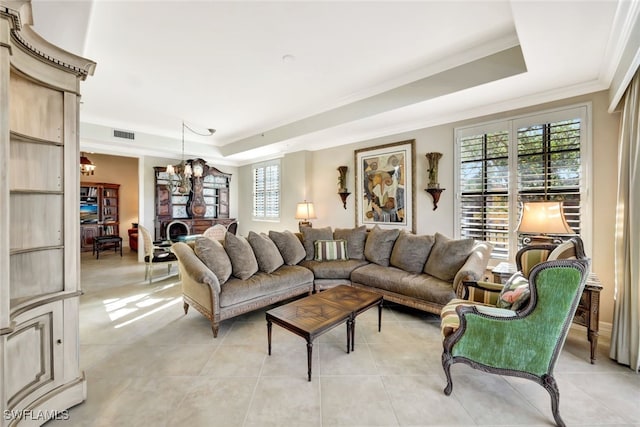 tiled living room featuring a raised ceiling, ornamental molding, and a notable chandelier