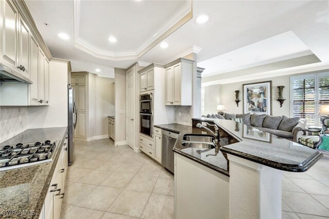 kitchen with sink, a breakfast bar area, stainless steel appliances, a raised ceiling, and crown molding