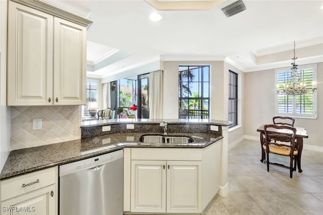 kitchen with dark stone countertops, sink, stainless steel dishwasher, and a tray ceiling