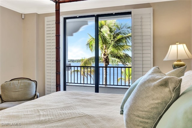 bedroom featuring multiple windows, ornamental molding, a water view, and access to outside