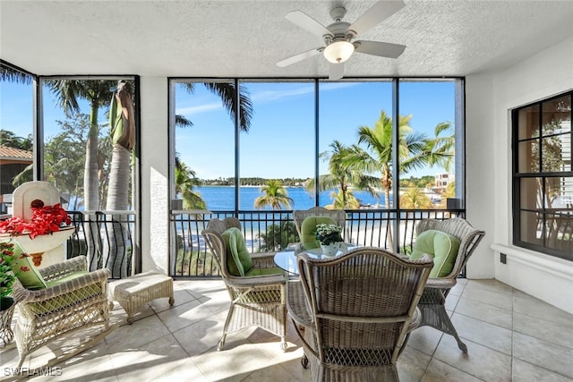 sunroom / solarium featuring ceiling fan and a water view