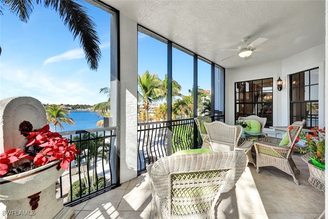 sunroom featuring a water view and ceiling fan