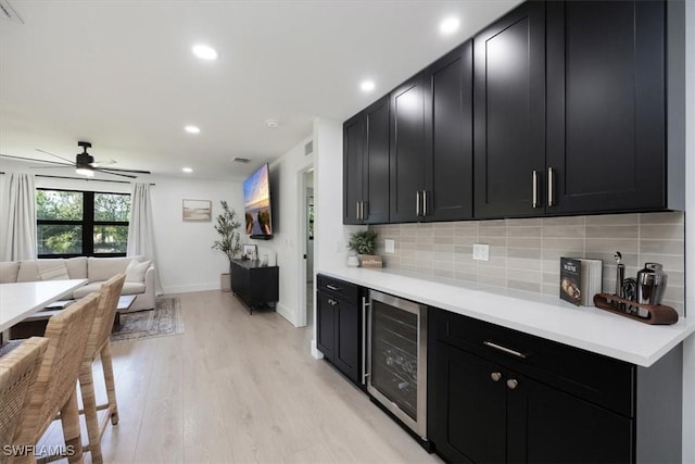 kitchen featuring tasteful backsplash, ceiling fan, beverage cooler, and light wood-type flooring