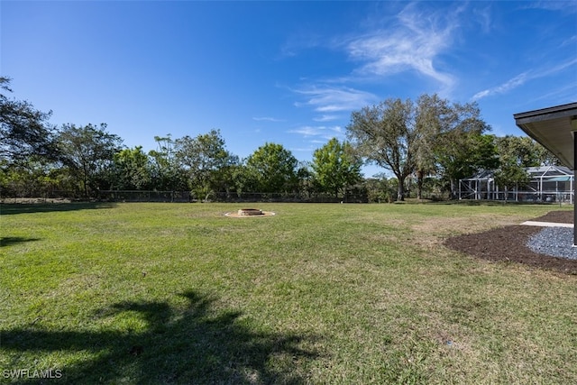 view of yard featuring a lanai and an outdoor fire pit