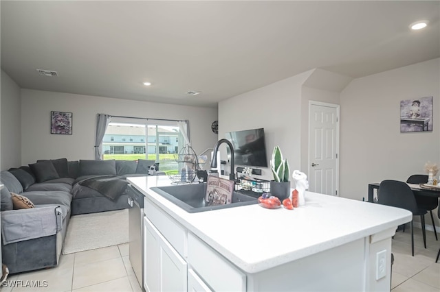 kitchen featuring an island with sink, dishwasher, light tile patterned flooring, and white cabinets