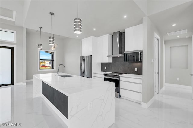 kitchen featuring appliances with stainless steel finishes, white cabinetry, an island with sink, sink, and wall chimney exhaust hood