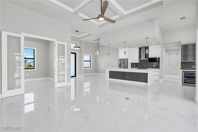 kitchen featuring wall chimney exhaust hood, coffered ceiling, white cabinetry, a kitchen island, and stainless steel appliances