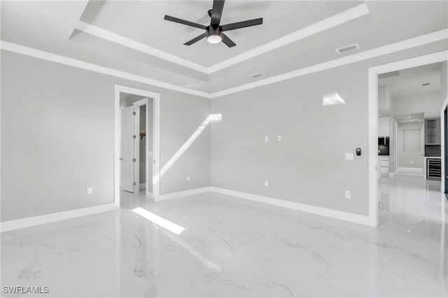 spare room with crown molding, ceiling fan, and a tray ceiling