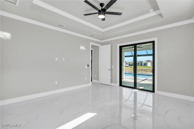 empty room featuring ornamental molding, ceiling fan, and a tray ceiling