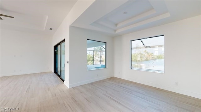 unfurnished room with a tray ceiling, light hardwood / wood-style flooring, and ceiling fan