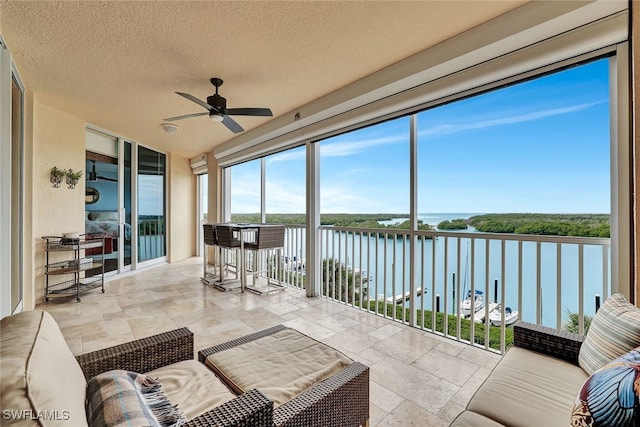 sunroom / solarium with a water view and ceiling fan