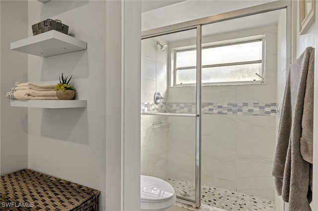 bathroom with a shower with door and toilet