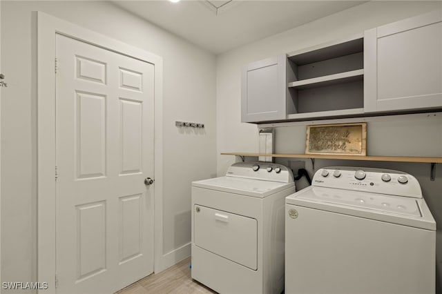 laundry area featuring cabinets, light hardwood / wood-style floors, and independent washer and dryer