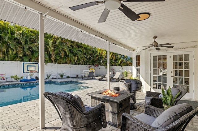 view of patio featuring french doors, a fenced in pool, ceiling fan, and a fire pit