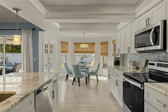 kitchen featuring appliances with stainless steel finishes, decorative light fixtures, tasteful backsplash, white cabinetry, and light stone countertops