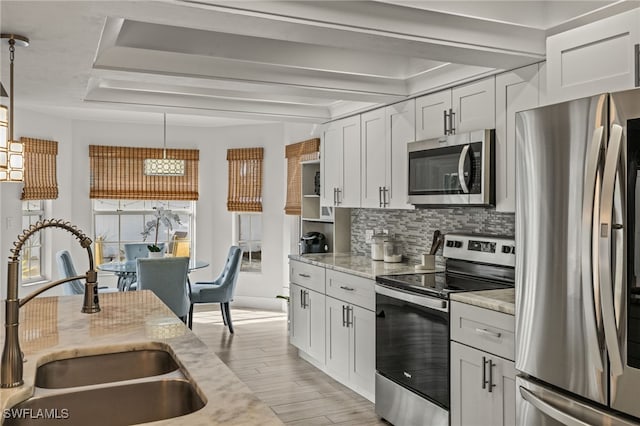 kitchen featuring sink, white cabinetry, light stone counters, decorative light fixtures, and appliances with stainless steel finishes