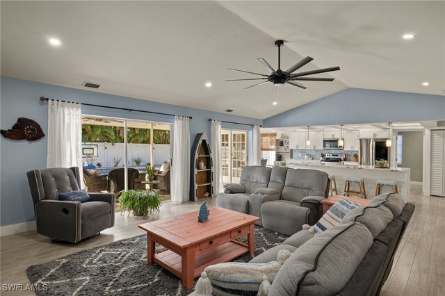 living area with lofted ceiling, ceiling fan, light wood-style flooring, visible vents, and baseboards