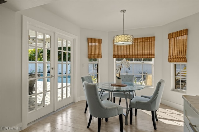 dining space with french doors, light wood-style flooring, and baseboards