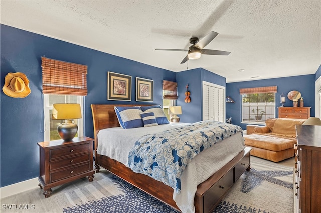 bedroom with a textured ceiling, a closet, light wood-type flooring, and a ceiling fan