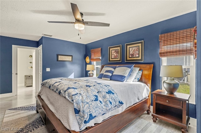 bedroom with a textured ceiling, wood finished floors, a ceiling fan, baseboards, and a closet