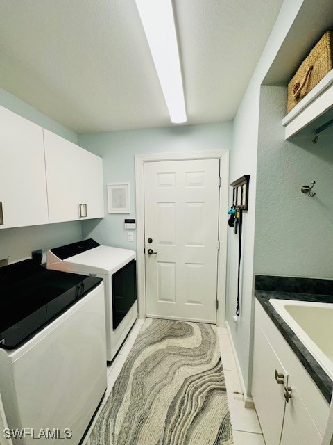 washroom with cabinets, separate washer and dryer, sink, and light tile patterned floors