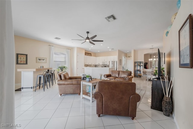 living room featuring ceiling fan with notable chandelier and light tile patterned floors