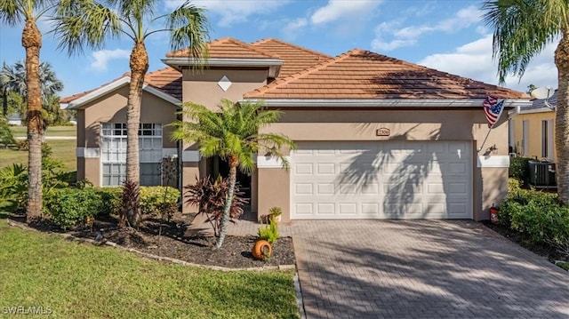 view of front of house featuring a garage, a front lawn, and central air condition unit