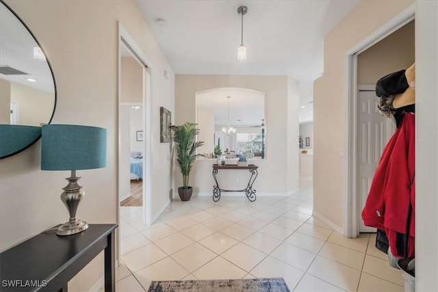 hallway featuring light tile patterned floors and a notable chandelier