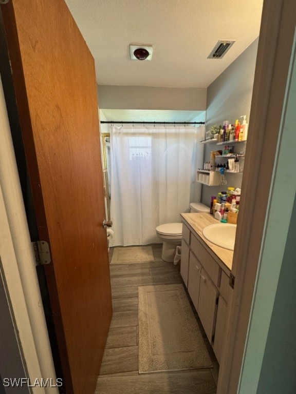 bathroom with vanity, hardwood / wood-style flooring, a textured ceiling, and toilet