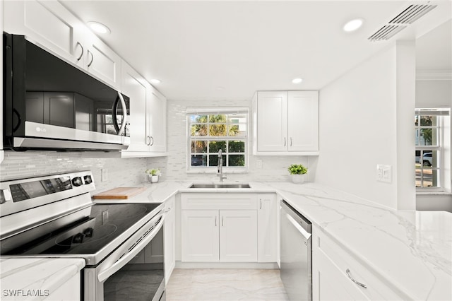 kitchen featuring visible vents, appliances with stainless steel finishes, light stone countertops, white cabinetry, and a sink