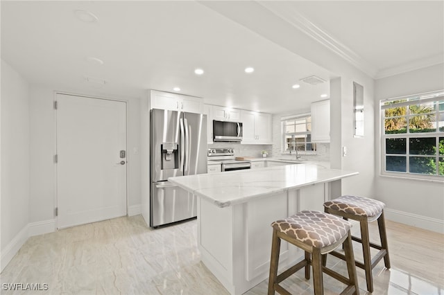 kitchen with light stone countertops, tasteful backsplash, appliances with stainless steel finishes, and white cabinets