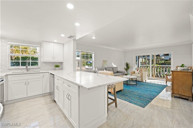 kitchen with a peninsula, white cabinetry, open floor plan, and a sink