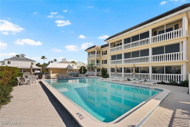 community pool with a patio area and fence